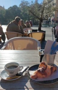 Coffee and a croissant on an outside terrace in the sun.